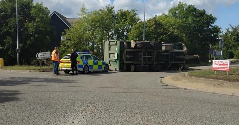 Road damaged after tractor overturns with trailer on roundabout